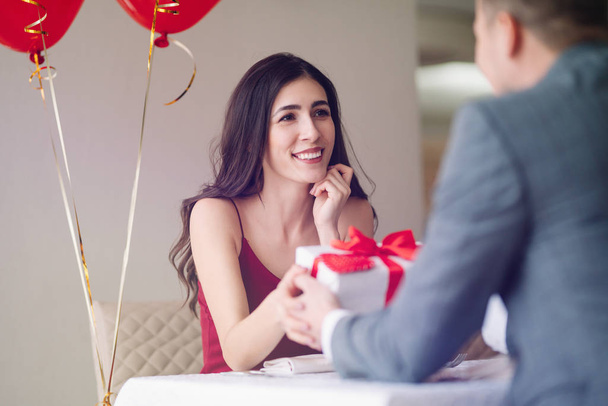 Valentine's Day concept. Happy couple in love with. A young loving couple celebrating Valentine's Day in the restaurant. Lovers give each other gifts. Romance restaurant for Valentine's Day- concept. - Φωτογραφία, εικόνα