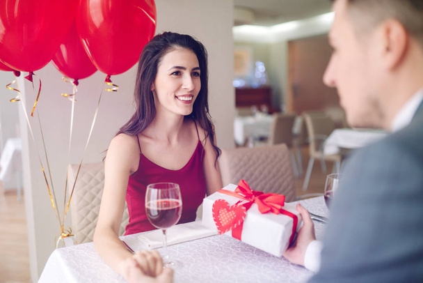Valentine's Day concept. Happy couple in love with. A young loving couple celebrating Valentine's Day in the restaurant. Lovers give each other gifts. Romance restaurant for Valentine's Day- concept. - Foto, Imagem