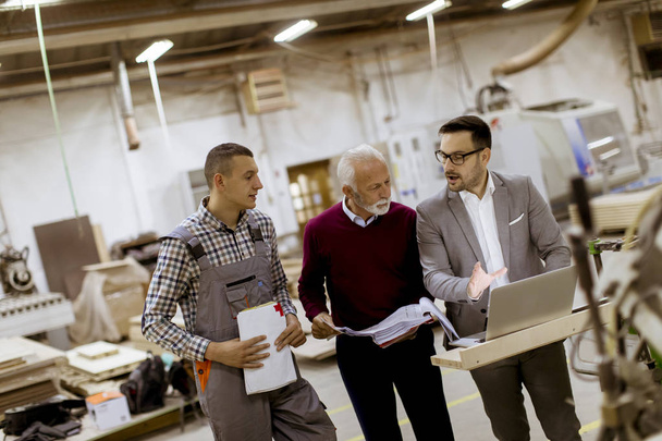 Portret trzech mężczyzn stojących i Dyskutować w fabryce mebli - Zdjęcie, obraz