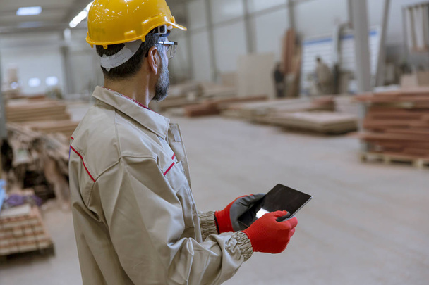 Handosme senior engineer with helmet controlling works in factory with digital tablet - Photo, Image