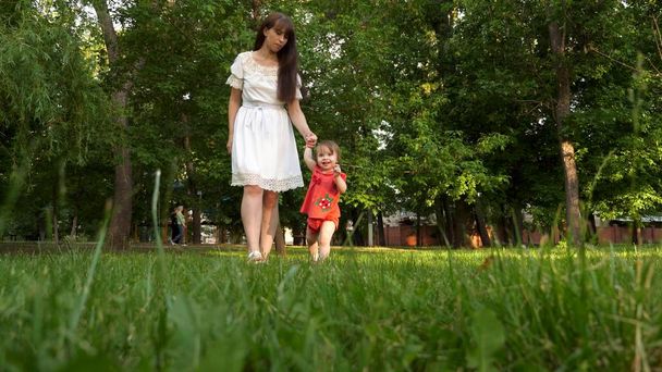 子供と母親夏市公園緑の芝生草と笑顔の上を歩く. - 写真・画像