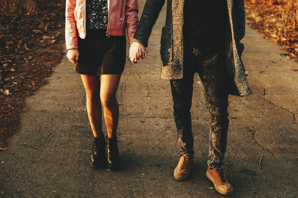 Felismerhetetlen fiatal férfi és a nő kezét, és séta a vidéken aszfaltút őszi napon. Termés pár vidéki úton járás - Fotó, kép