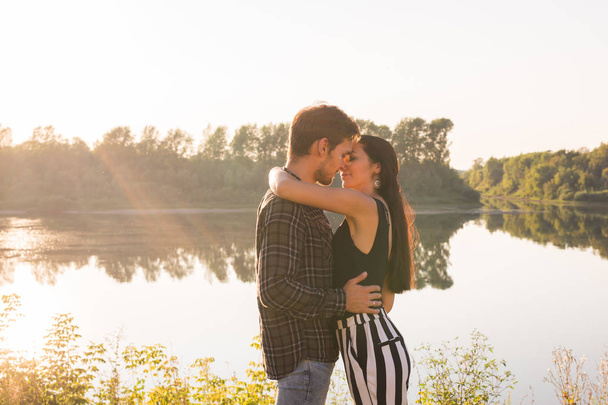 Love, romantic and nature concept - young couple hugging near the lake - Photo, Image