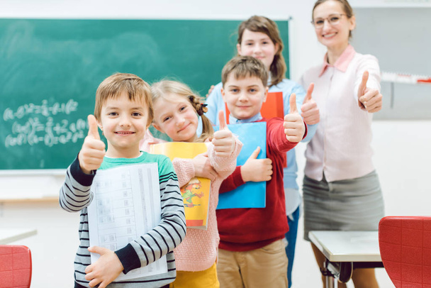 Ученики и учитель показывают большой палец вверх в школе весело
 - Фото, изображение
