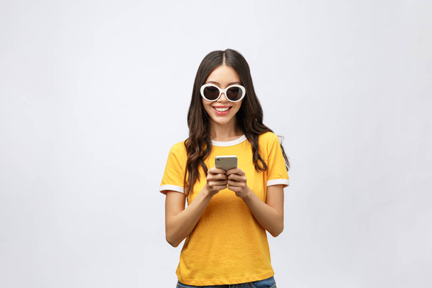 Content calm trendy nice cute adorable lovely attractive brunette caucasian girl with wavy hair in casual shirt, playing game in phone, isolated over grey background. - Fotó, kép