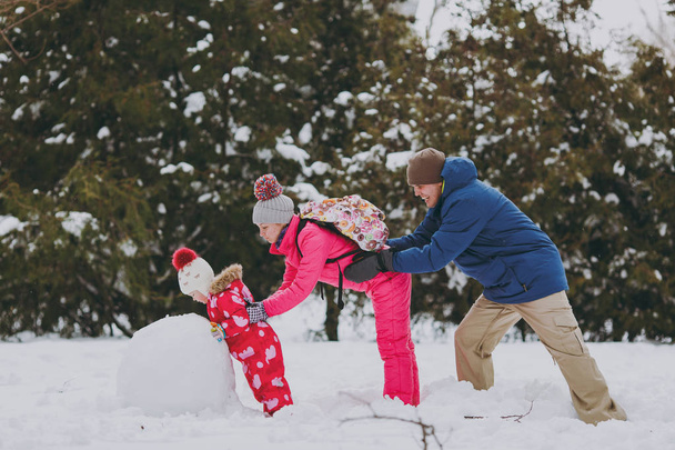 家族の女性も少女再生、暖かい服で作る雪だるま、雪の公園または森林の屋外でお互いを押して. します。冬の楽しみ、休日レジャー。愛の関係家族のライフ スタイル コンセプト - 写真・画像