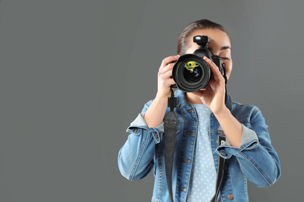 Young woman with camera and space for text on gray background. Professional photo studio - Foto, immagini