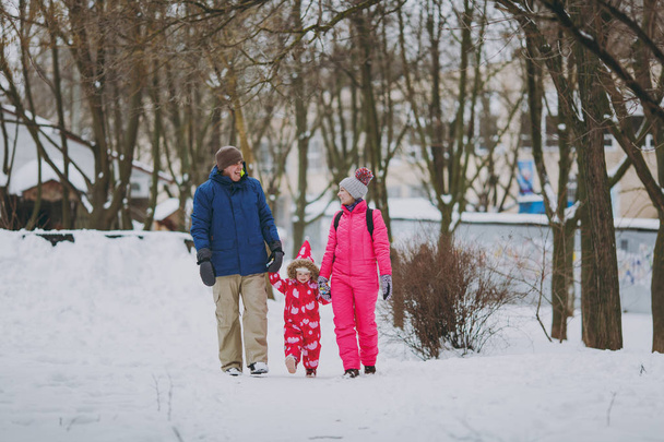 Nevetve a család nő, a férfi és a kislány a téli meleg ruhát, séta a havas park vagy az erdő a szabadban. Téli szabadidős szórakozás a nyaralás. Szeretik gyerekkori kapcsolat családi emberek életmód fogalma - Fotó, kép