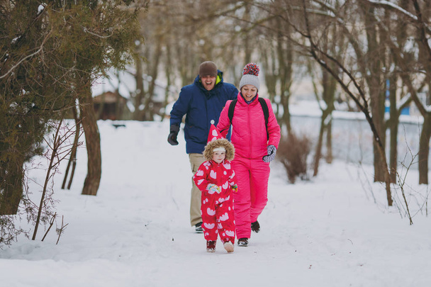 陽気な家族の女性はランニング、雪の公園でウォーキングの暖かい服の少女を男性またはフォレストの屋外。冬の楽しみ、休日レジャー。愛小児関係家族の人々 のライフ スタイル コンセプト - 写真・画像