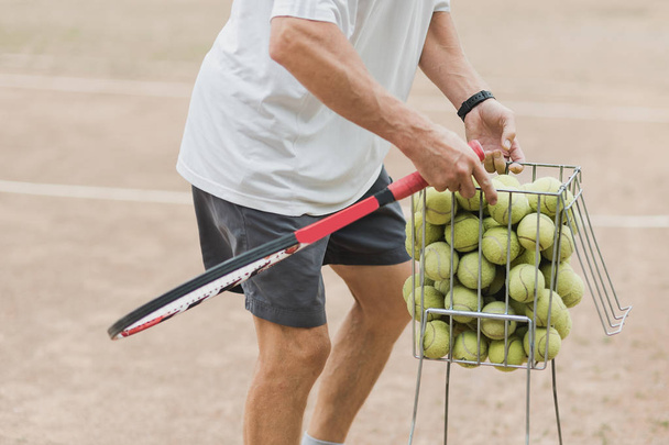 coach collecting tennis balls in basket after training, Tennis lesson concept - Fotoğraf, Görsel