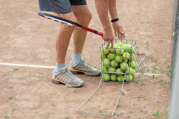 coach collecting tennis balls in basket after training, Tennis lesson concept - Фото, изображение