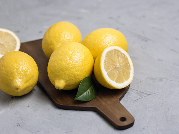 Whole and sliced lemons on wooden cutting board. Organic fresh citrus fruits - Foto, imagen