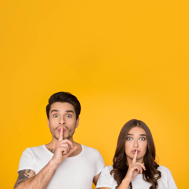 Young couple showing silence gesture putting finger on lips - Photo, Image