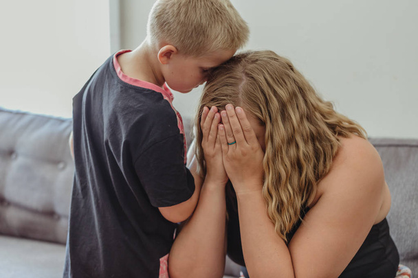 young boy concerned for his mother and leaning into her comforting her as she cries - Photo, Image