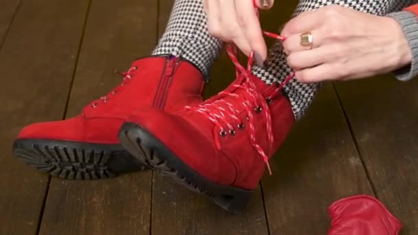 Beautiful woman gets her red shoes and tie shoelaces on dark wooden background - Footage, Video
