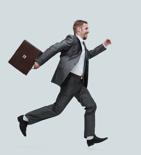 side view.cheerful businessman with briefcase stepping forward - Фото, изображение