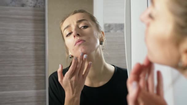 Mädchen mit Akne im Gesicht ist ein Badezimmer neben dem Spiegel - Filmmaterial, Video