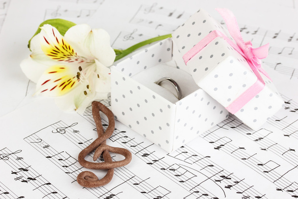 Chiave di violino, fiore e scatola con anello nuziale su sfondo musicale
 - Foto, immagini