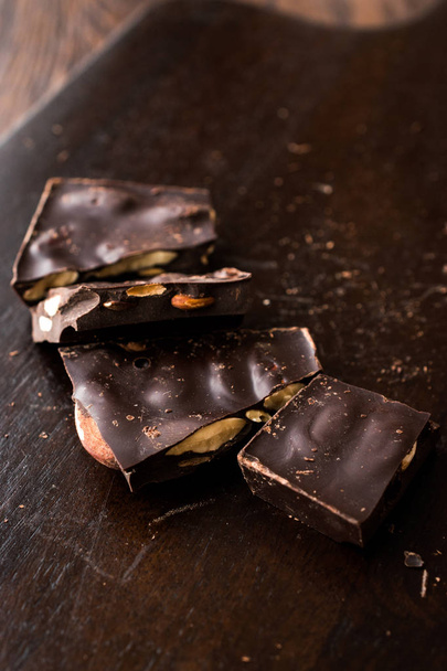 Piezas de chocolate de almendras amargas en la superficie de madera oscura. Snacks ecológicos
. - Foto, imagen
