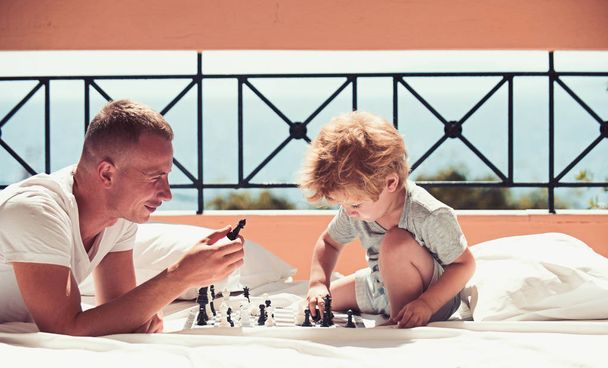 Child play chess with father. Love and trust as family values. Family travel with kid on fathers day. Summer vacation of happy family. father with son on balcony play chess - Valokuva, kuva