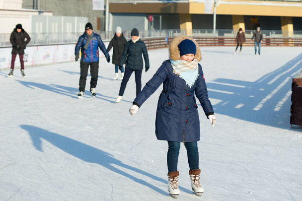 MOSCOW, RUSSIA - JANUARY 22, 2019: Young woman in blue and people skating in VDNKh on winter sunny day. VDNKh is permanent general purpose trade show and amusement park. - 写真・画像
