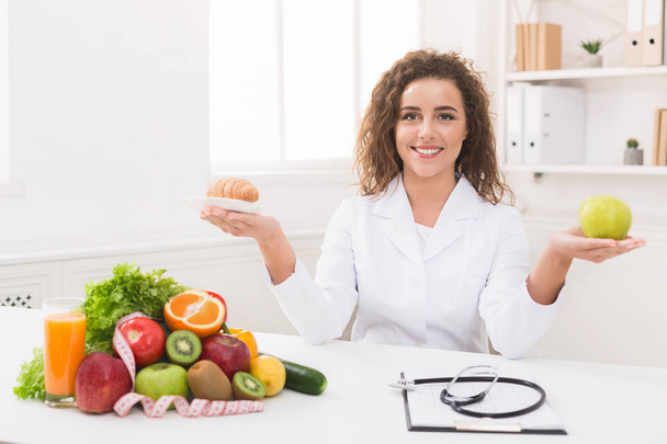 Nainen ravitsemusterapeutin tilalla hedelmiä ja croissant käsissä
 - Valokuva, kuva