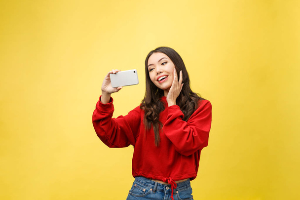 Sorridente ragazza che fa foto selfie su smartphone su sfondo giallo - Foto, immagini