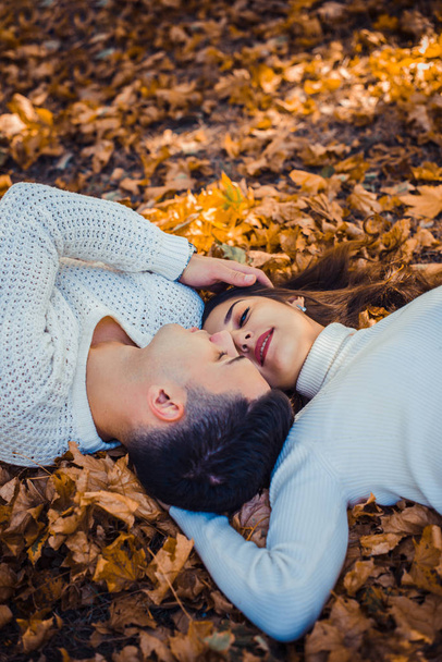 Çekici çift beyaz giyen sarılma ve birbirine bakarak parkta yatıyor - Fotoğraf, Görsel