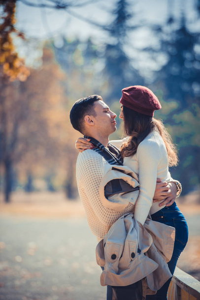 Couple in love is looking very happy while standing on the bridge in autumn park - Photo, Image