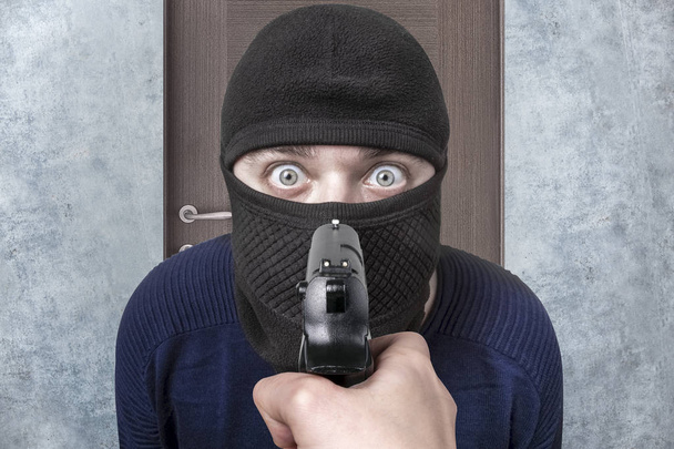 Gun célja a bűncselekmény balaclava, a kép a háttérben, az ajtó, elkapta a tolvajt fogalma - Fotó, kép
