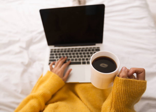 Frau benutzt Laptop mit leerem Bildschirm und trinkt Kaffee - Foto, Bild