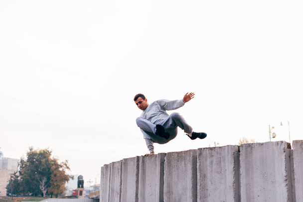 Caucasian man trains parkour while jumping over a high top. - Zdjęcie, obraz