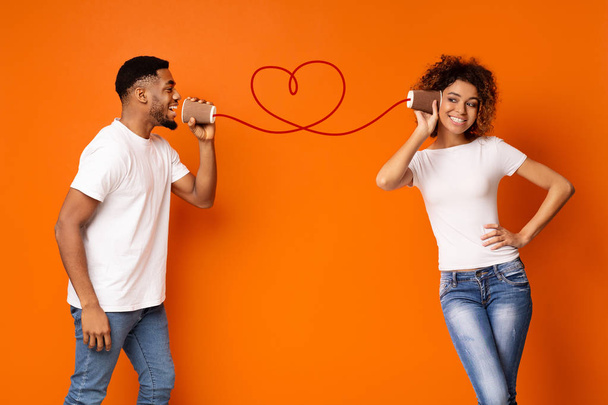 Jovem casal preto com pode telefone no fundo laranja - Foto, Imagem