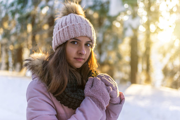 Close-up portrait of beautiful young woman in winter forest on sunset. - 写真・画像