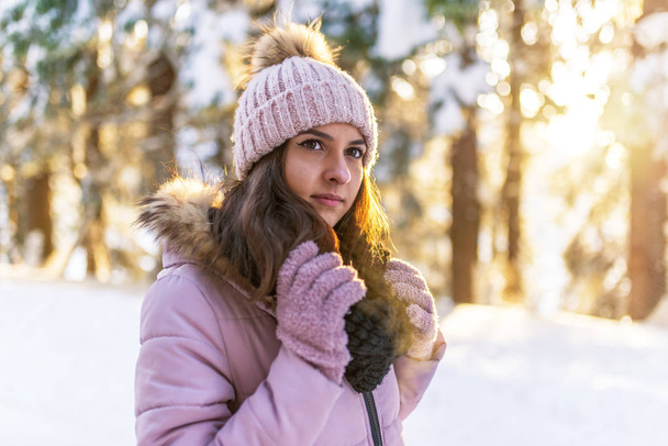 Close-up portret van mooie jonge vrouw in winter bos op zonsondergang. - Foto, afbeelding