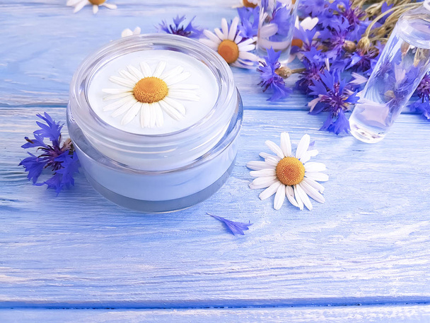 cosmetic cream, chamomile flower, cornflower, wooden background - Φωτογραφία, εικόνα