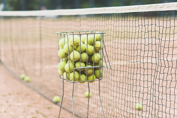 Tennis balls in basket on background of tennis court  - Photo, Image