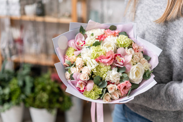 pięknych świeżych ciętych bukiet kwiatów mieszane w ręce kobiety. Praca w kwiaciarni Kwiaciarnia. Delikatne pastelowe odcienie kolorów - Zdjęcie, obraz