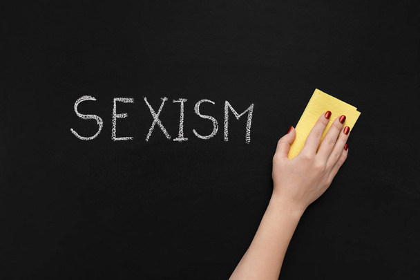 Sexism is written on chalkboard and hand with sponge - Fotoğraf, Görsel