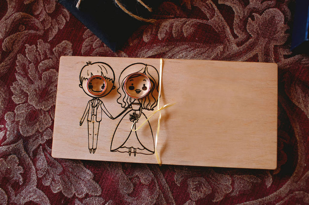 madera contrachapada, una tabla con una imagen de una chica y un chico, una novia y un novio, cerca de anillos de boda y un lugar para el texto
. - Foto, Imagen
