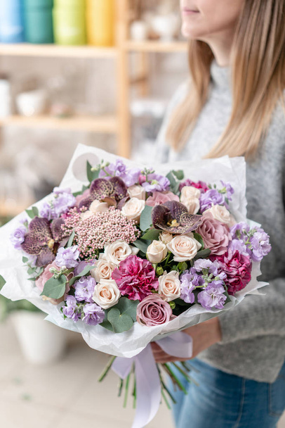 beautiful fresh cut bouquet of mixed flowers in woman hand. the work of the florist at a flower shop. Delicate Pastel tones color - Fotoğraf, Görsel