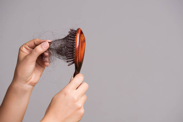 ヘルスケアの概念。女性は長い損失髪とブラシから彼女の髪を引っ張って、彼女のブラシを表示します。. - 写真・画像