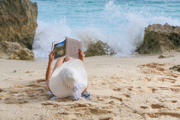 Genç kadın plajda, vaktinizi dergi okuma - Fotoğraf, Görsel