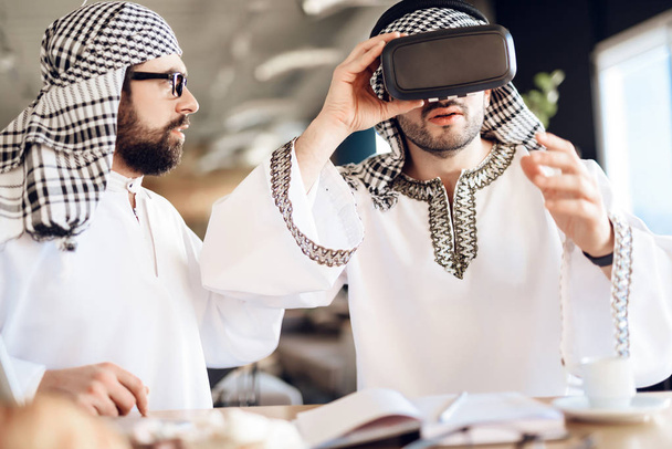 Two arab businessmen using virtual reality at table at hotel room. - Photo, Image