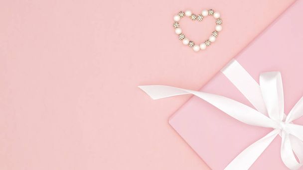 Valentine tai naisten päivä vaaleanpunainen lahja valkoinen keula nauha koristeltu pieniä sydämiä koralli paperille tausta. Käsite sisustus rakkaus päivä tai syntymäpäivä. Litteä pano. Kopioi tila
 - Valokuva, kuva