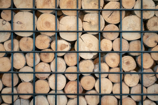 Foto abstracta de una pila de troncos de madera natural fondo en marco de metal negro para decoración de diseño de interiores
 - Foto, imagen