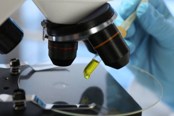 Laboratory assistant doing analysis with urine sample and microscope, closeup - Foto, Imagem
