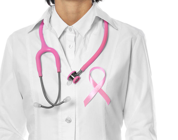 Vrouwelijke arts met roze lint en stethoscoop op witte achtergrond, close-up. Borst kanker concept - Foto, afbeelding