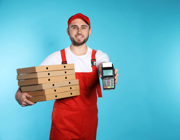 Smiling courier with pizza boxes and payment terminal on color background. Space for text - Фото, зображення