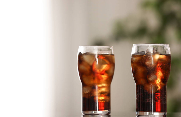 Glasses of cola with ice on table against blurred background. Space for text - Фото, зображення